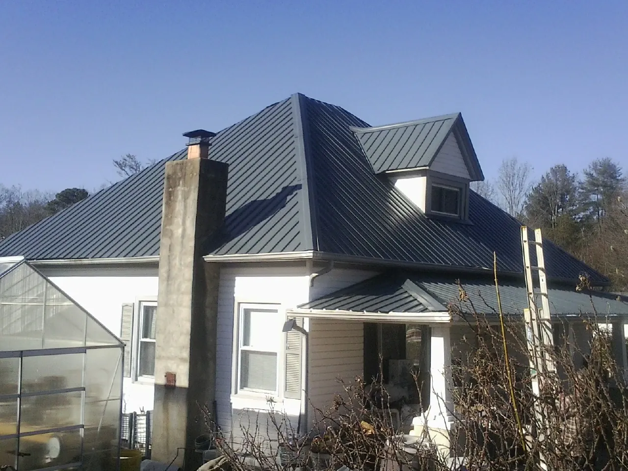 Dark blue standing seam metal roof on a white farmhouse with dormer — Slate & Tile Roof Repair by Roofing Brothers in Zanesville
