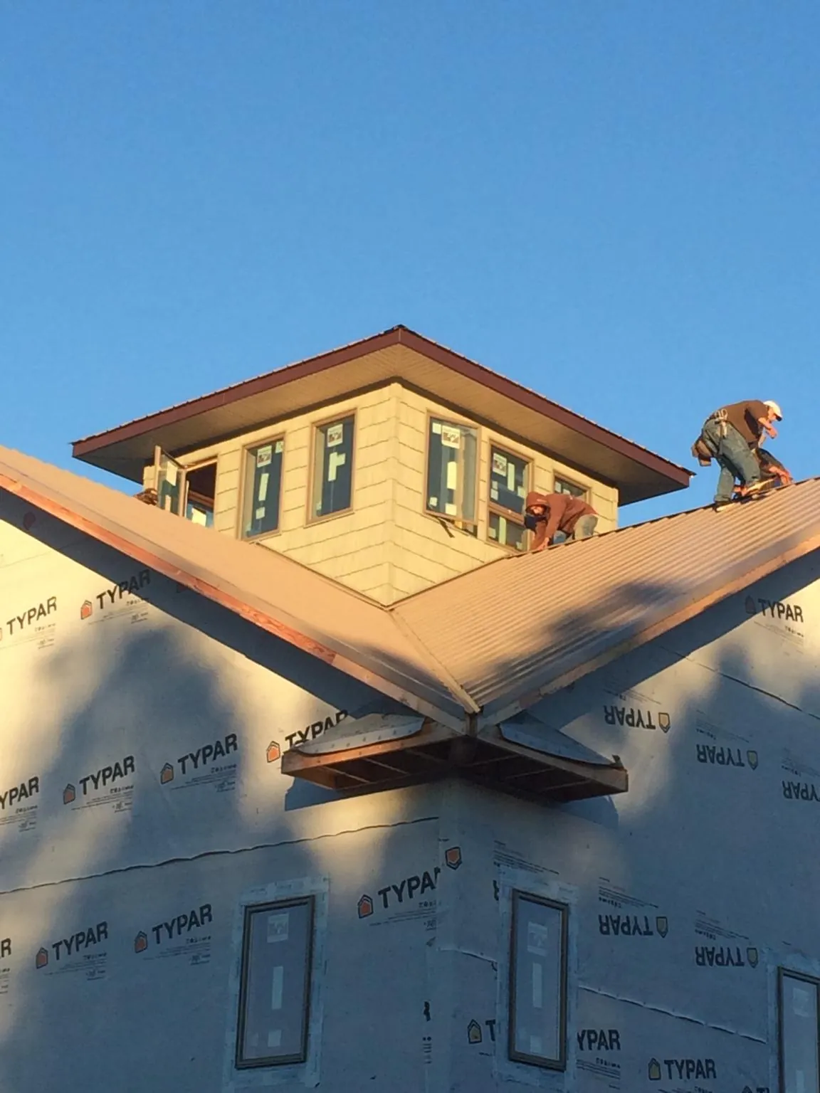 Roofers working around a rooftop cupola on a new metal roof at sunset — Roof Waterproofing in Zanesville by Roofing Brothers